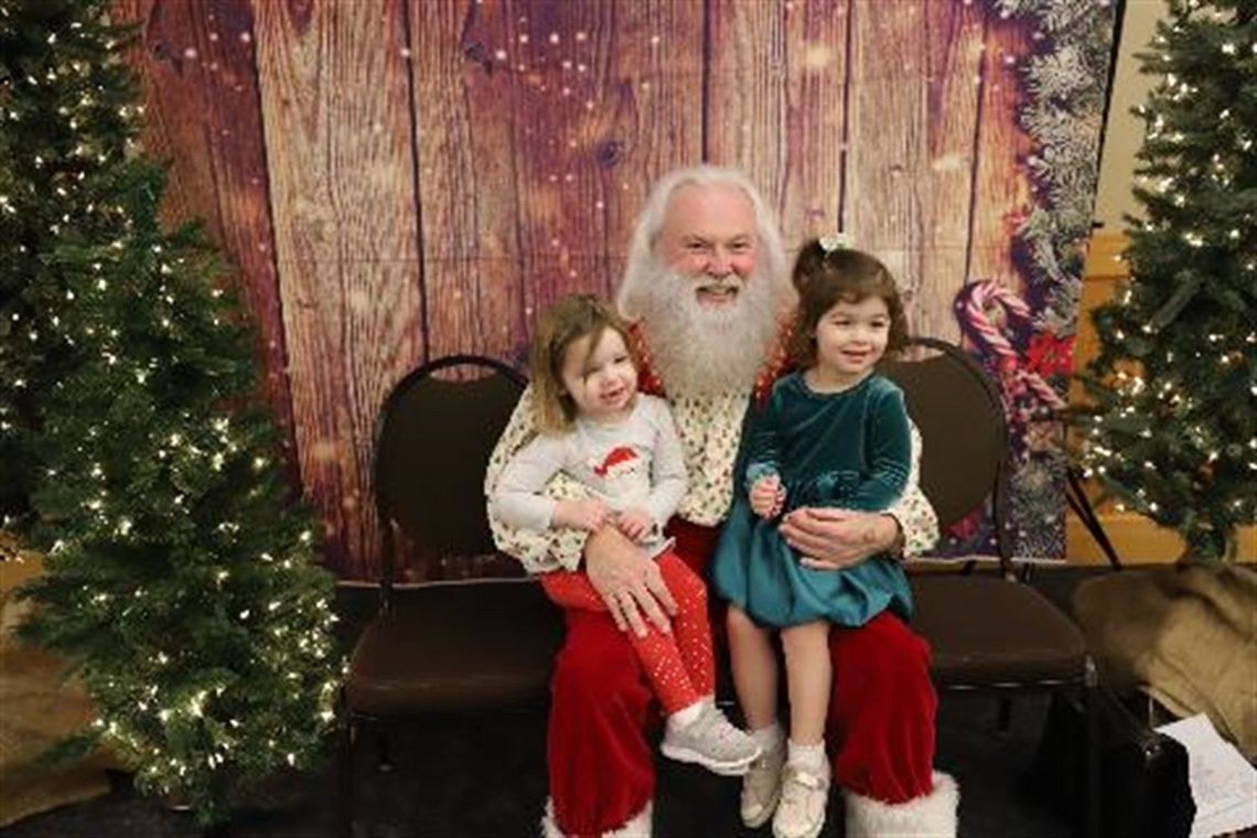 Two girls posing for a photo with Santa Claus